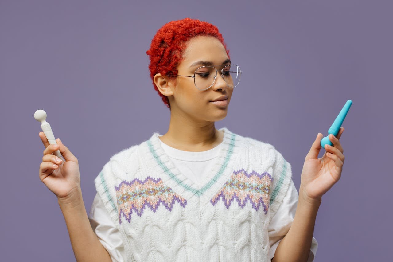 A stylish young adult holding a vibrator and wand, expressing modern sensuality.